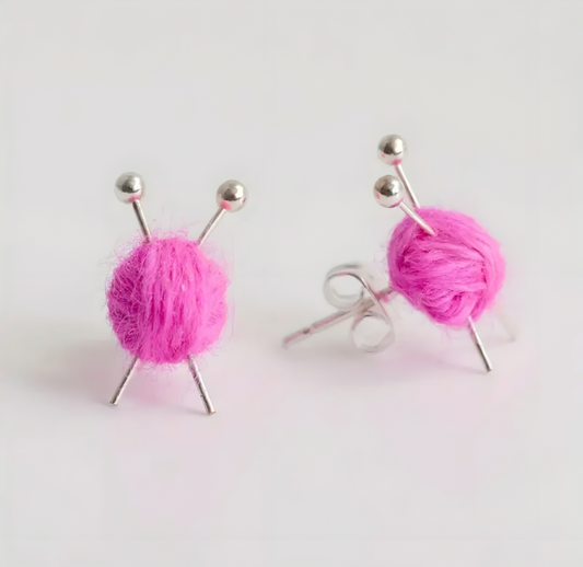 Pink yarn ball earrings on a white background